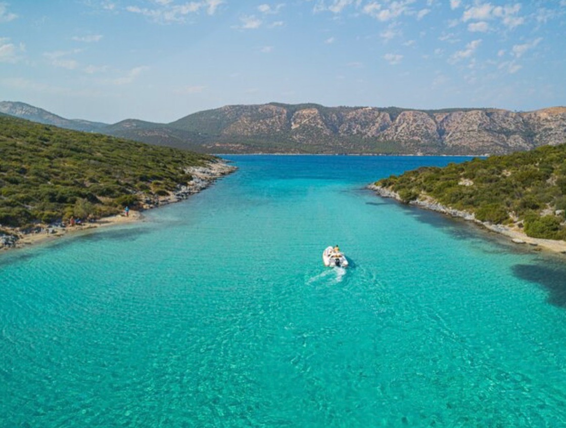 Τιρκουάζ λιμνοθάλασσα στη Σάμο με σκάφος να πλέει στα ρηχά